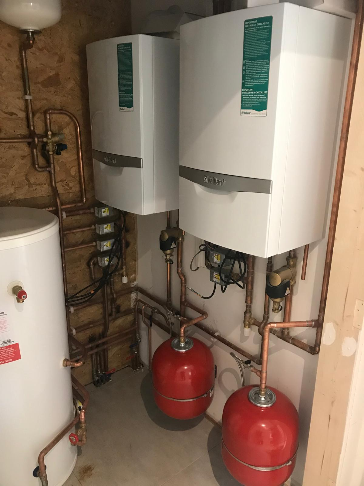 Twin Vaillant boilers with unvented hot water cylinder, red expansion vessels and neat copper pipework — full boiler replacement by Premier Heating