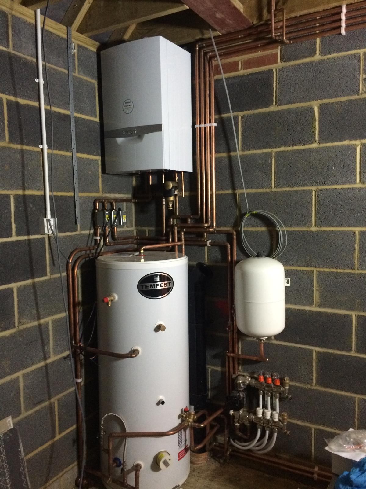 Vaillant boiler and unvented cylinder installation against a black stone wall by Premier Heating